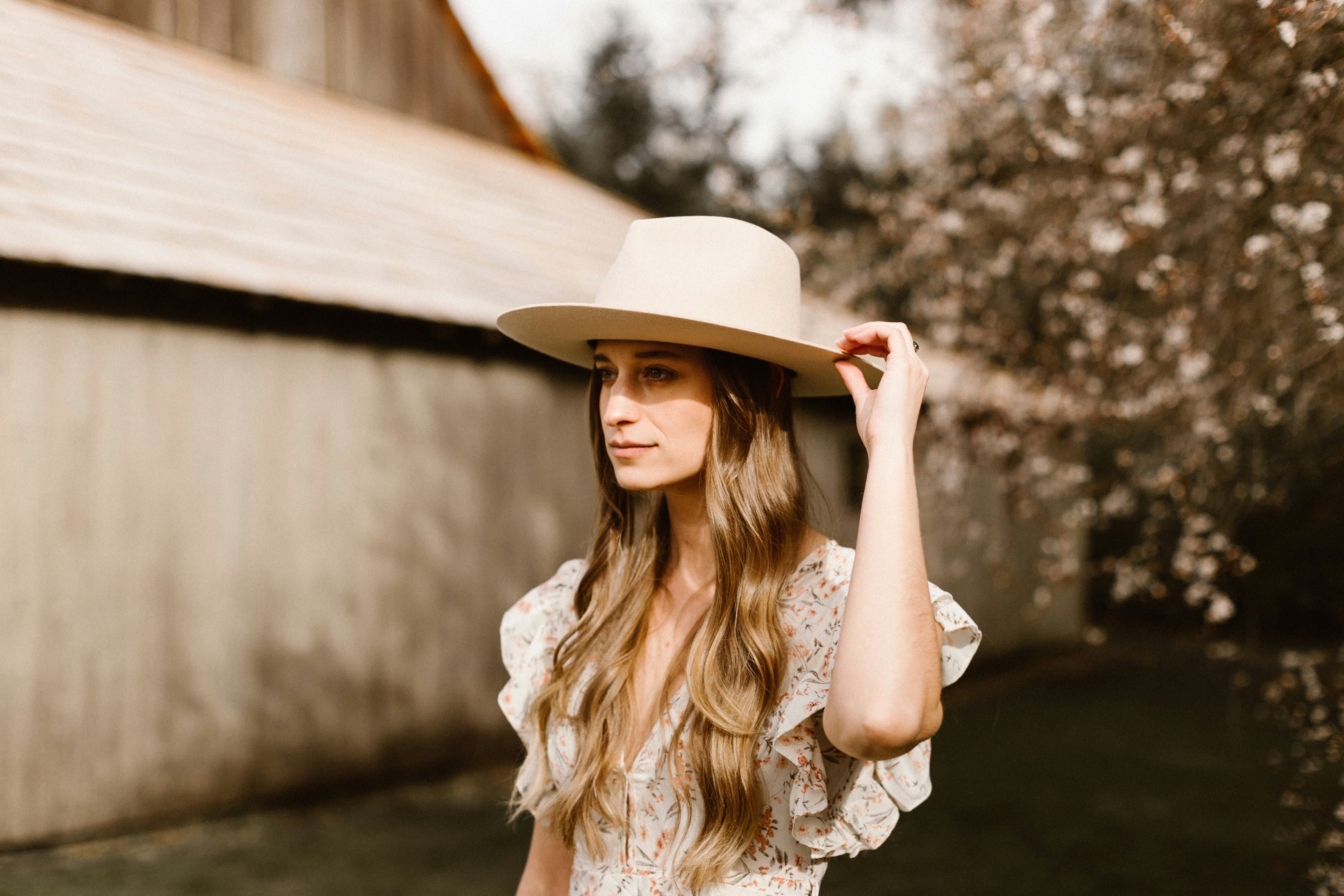 woman in white sun hat and white floral shirt